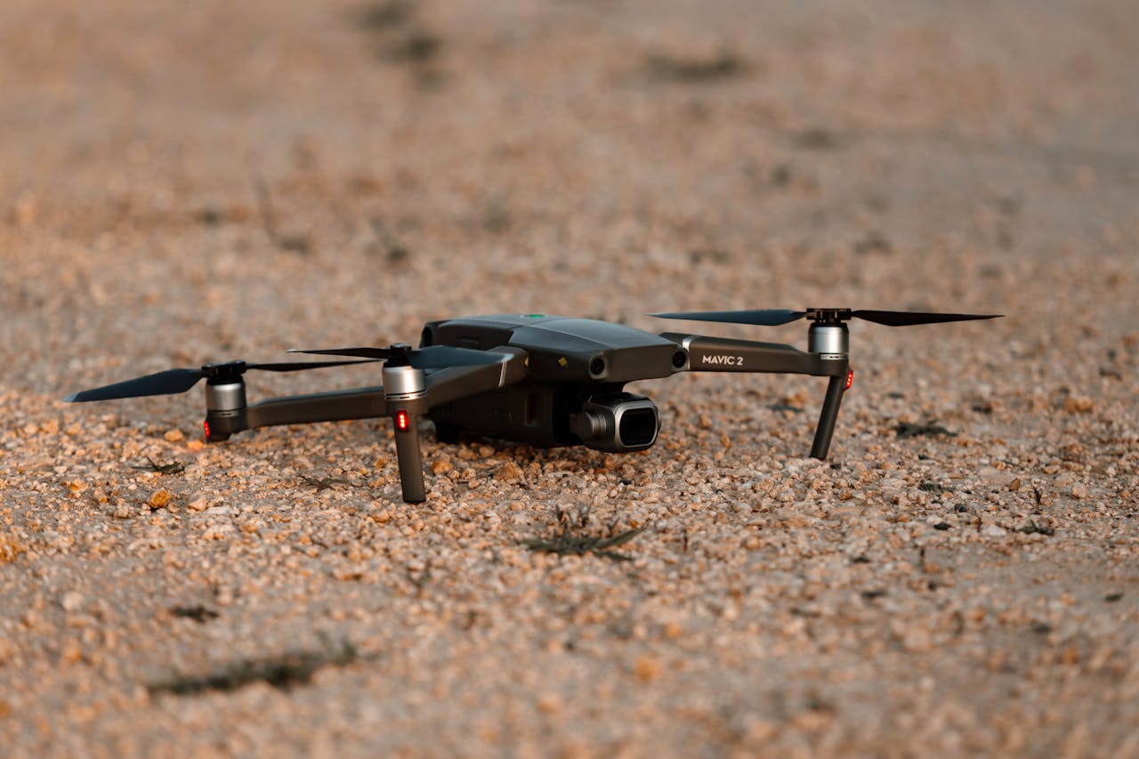 A detailed photo of a sleek drone resting on a gravel surface, ready for takeoff.